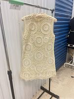 Front view of cream crochet mini dress hanging on rack