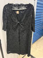 Front view of lace overlay on hanger showing satin bow and floral lace