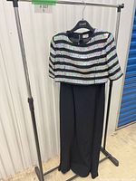 Front view of sequined top over black dress hung on rack