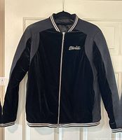 Front view of black velour bomber jacket on hanger, showing zipper and Starlite chest embroidery