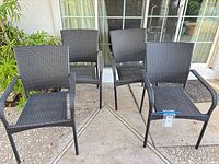 Front view of all four matching patio armchairs, showing woven seats/backs, armrests and legs
