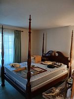 Full view of assembled four-poster bed frame with mattress and tall turned posts