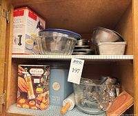 Cabinet shelves with glass bowls, metal bowls, boxed bakeware, rolling pin