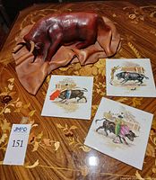 Bull sculpture on ornate table with three illustrated coasters visible