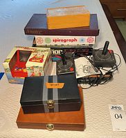 Stacked boxed games and electronic items showing variety