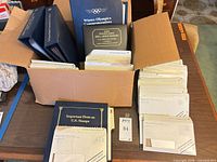 Open box with three albums and stacks of first day cover envelopes