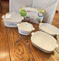 Group shot of four CorningWare dishes with two lids and boxed Pyrex set