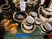 Group shot of dinner plates, teacups, saucers, teapot, creamer, sugar bowl, and vases in cabinet