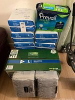 Stacked packs of McKesson Ultra Briefs, box of Depend, packs of Depend Protection Plus, pack of Prevail Per-Fit 360