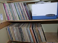 Two shelves filled with numerous vinyl LPs beside a Bankers Box