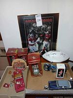 Group shot of framed poster, bobbleheads, signed football, tailgate truck, models