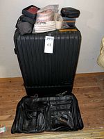 Suitcase upright with accessories stacked on top and leather duffle in front