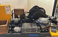 Group shot of all cameras, radio, binoculars, film and cases on table