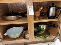 Cabinet view showing copper pans, wooden mortar & pestle, electric percolator, Pyrex bowl, kitchen torch box, Presto pot, green glass bowl