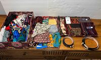 Overview of lot showing boxes filled with multiple scarves, two folded pashmina-style wraps, and two leather belts