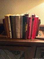 Row of eleven hardcover books shown between wooden bookends