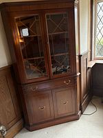 Full view of walnut corner cabinet showing upper glass doors, drawer, lower cabinet doors