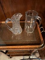 Cut crystal pitcher and clear glass jug side by side on wooden cart