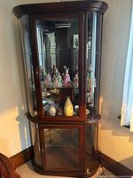 Full view of cherry wood curved glass corner cabinet with upper display and lower storage sections
