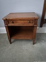 Front view of walnut night table showing drawer, shelf, legs