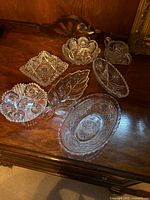 Seven assorted cut crystal dishes displayed on wooden surface