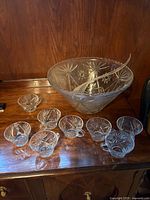 Cut crystal punch bowl with starburst pattern, eight matching cups, clear ladle