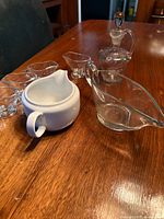 Seven-piece assortment of sauce servers including glass gravy boat, ceramic server, cruet, and four small dip bowls