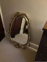 Front view of silver-tone ornate wall mirror leaning against wall