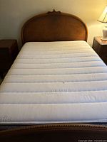 Full view of bed showing curved oak headboard, mattress present for scale