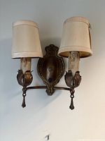 Front view of brass double arm wall sconce with shades attached