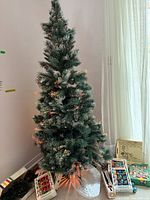 Full view of slim flocked tree with lights, plastic stand, ornament boxes, tray and spare lights