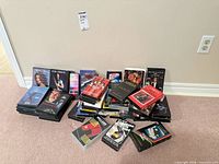 Full lot of mixed VHS and DVDs stacked on floor