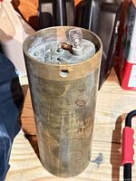 Full view of brass cylindrical safe deposit tube with key inserted in top lock