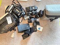 Group shot showing Sony Handycam, Minolta 7000 body with lens, additional lens, flash, binoculars, camera bag and accessories