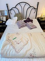 Full-size bed with black scroll headboard and bedding removed for view