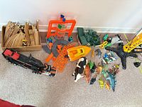 lot overview showing crane, wooden tracks, truck, playset parts, boat, animals, dinosaurs, army vehicles