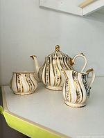 Teapot, creamer and sugar bowl grouped on shelf