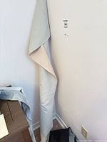 Full length of rolled fabric standing in corner with protective outer wrap and small off-cut at base