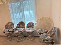 Five wicker chairs lined up: four swivel pedestal, one peacock chair