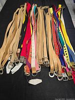 Spread of tan leather and coloured fabric belts on table
