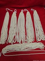 Five bundled groups and one loose bundle of pearl bead strands on red background