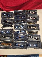 All 20 pairs of Jianlong sunglasses laid out with pouches visible
