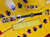 Open box showing wristwatch, four loose bezels and stack of additional boxed sets