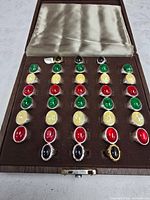Open wooden display case showing 25 costume rings in rows