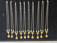 Full view of eleven silver-tone necklaces laid flat on black background