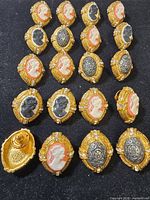 Grid of gold-tone cameo lapel pins showing quantity and designs