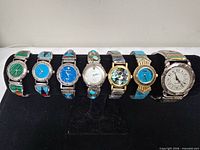 Front view of the seven stone-inlaid wristwatches on display bar