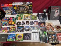 Overview of boxed peripherals, joystick and array of PC games on table