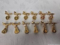 Front view of all twelve gold-tone tie clips, six apples and six pears