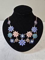 Full view of floral statement necklace on display bust